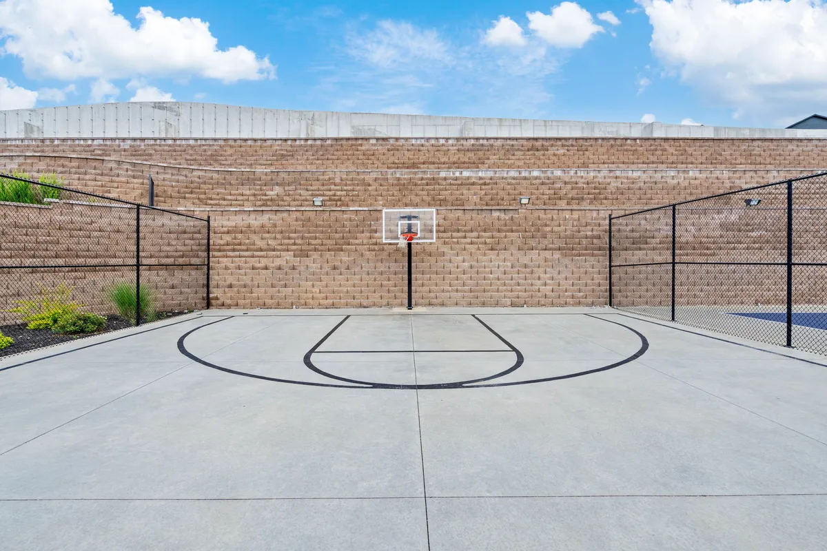 A well-maintained outdoor basketball court with hoop, court lines, and fencing, set against a backdrop inviting active play and friendly competition. The scene is lively and energetic, perfect for group games and tournaments.