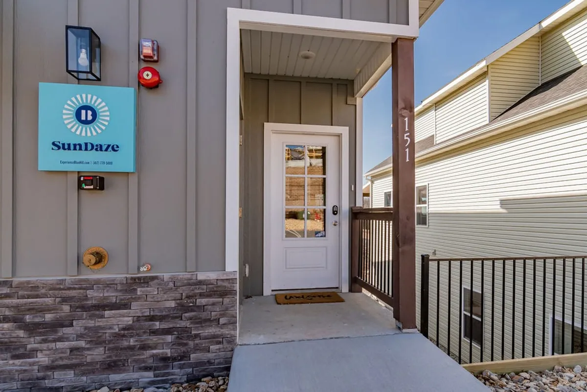 This exterior image shows the welcoming entrance to SunDaze Lodge, complete with the SunDaze sign and a stone wall, evoking a sense of arrival and hospitality. The space appears inviting and ready to accommodate guests and their pets, setting the stage for a comfortable, pet-friendly stay from the moment of arrival.