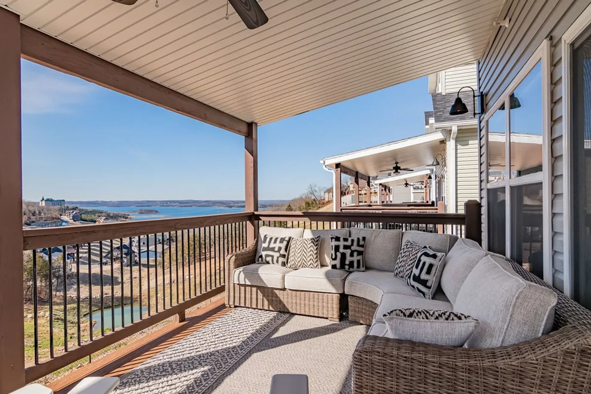 This exterior image features a cozy sectional sofa set on a deck with a view of water, accented by decorative cushions and an outdoor railing. The serene atmosphere highlights the inviting outdoor living space perfect for relaxing, entertaining, and enjoying the fresh air. The proximity to nature and open space aligns with the pet-friendly theme, suggesting a comfortable setting for dog owners to unwind while keeping an eye on their pets.