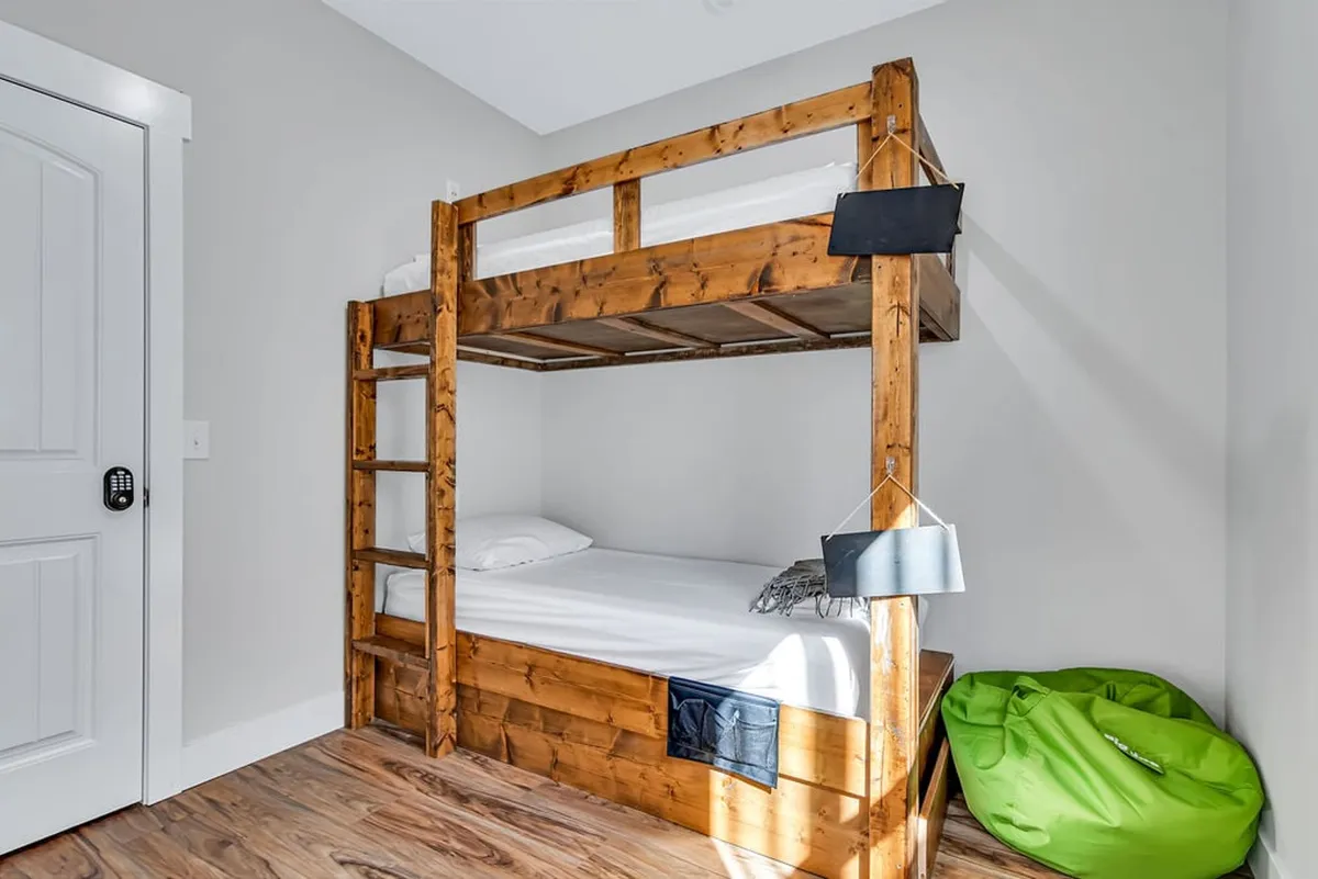 A playful kid-friendly bunk room with a bunk bed, bean bag chair, and wood flooring. The setup suggests a cozy space ideal for bedtime stories, naps, or imaginative play, designed specifically for younger guests.